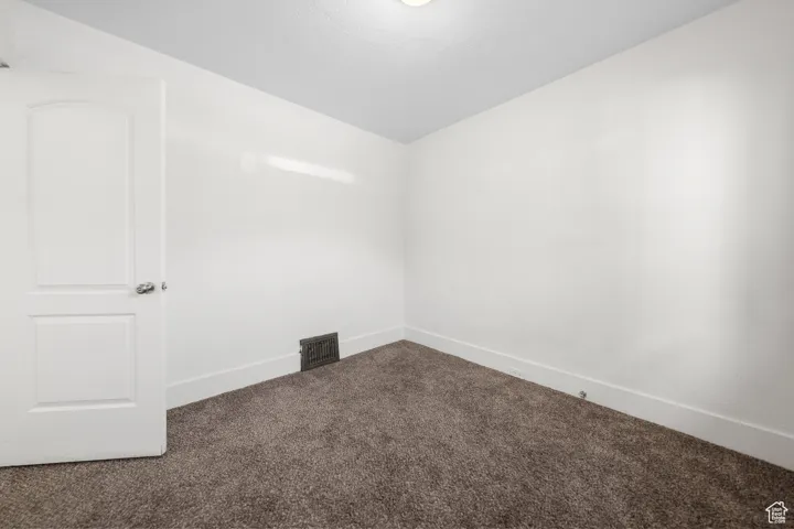 Empty room with carpet and vaulted ceiling