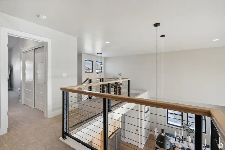 Hall with an upstairs landing, light colored carpet, and recessed lighting