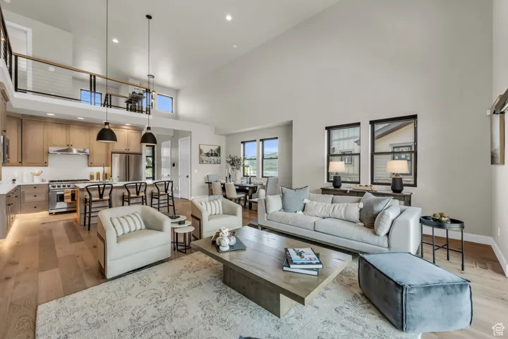Living area featuring light wood-style floors, a high ceiling, and recessed lighting
