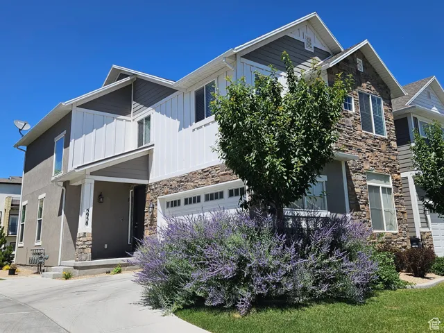 Craftsman house with stone siding, board and batten siding, an attached garage, driveway, and stucco siding