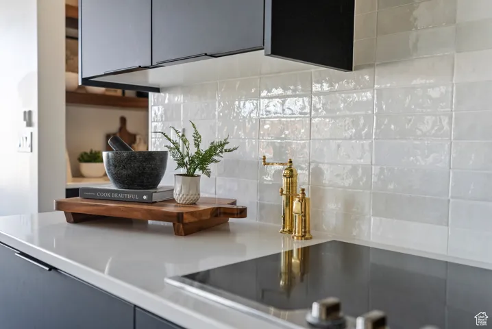 Kitchen view of black electric stovetop, backsplash, and light countertops