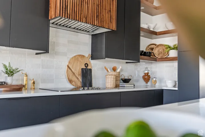Kitchen view of open shelves, modern cabinets, wall chimney exhaust hood, tasteful backsplash, and light countertops