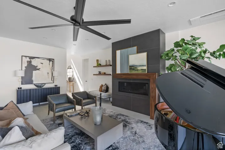 Living room featuring a ceiling fan, recessed lighting, and a fireplace