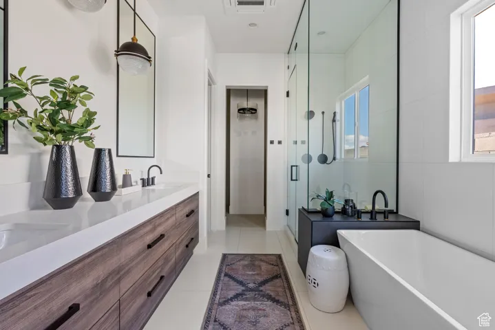 Bathroom with a shower stall, double vanity, a soaking tub, and tile patterned flooring
