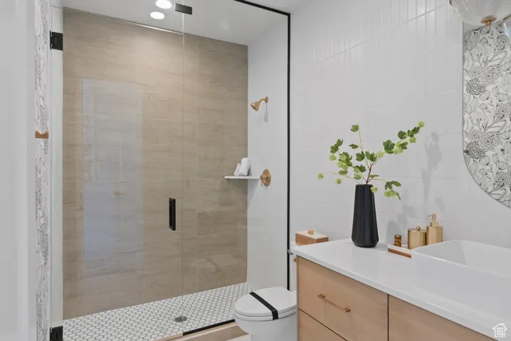 Bathroom featuring tile walls, vanity, and a stall shower