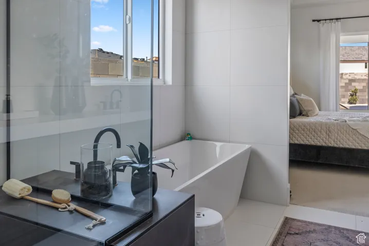 Ensuite bathroom featuring a bath, vanity, and tile patterned flooring