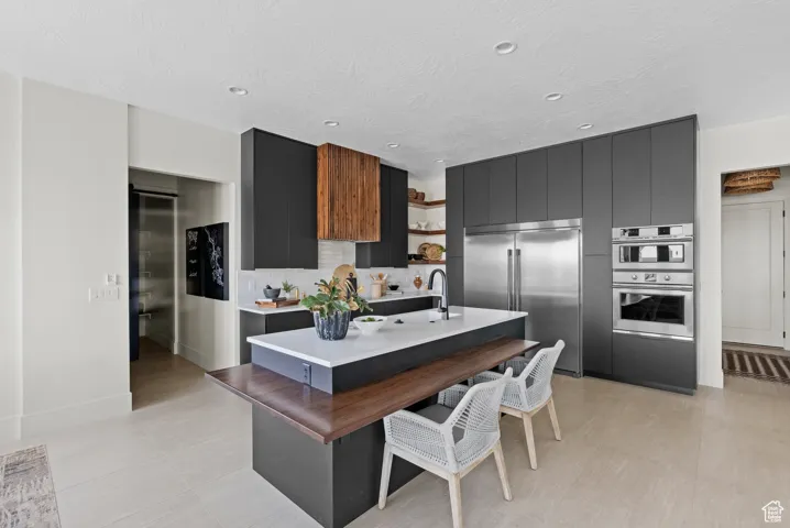 Kitchen featuring open shelves, appliances with stainless steel finishes, modern cabinets, dark cabinetry, and light countertops