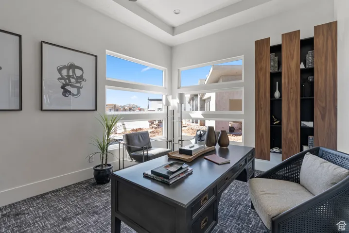 Office area featuring dark carpet and baseboards