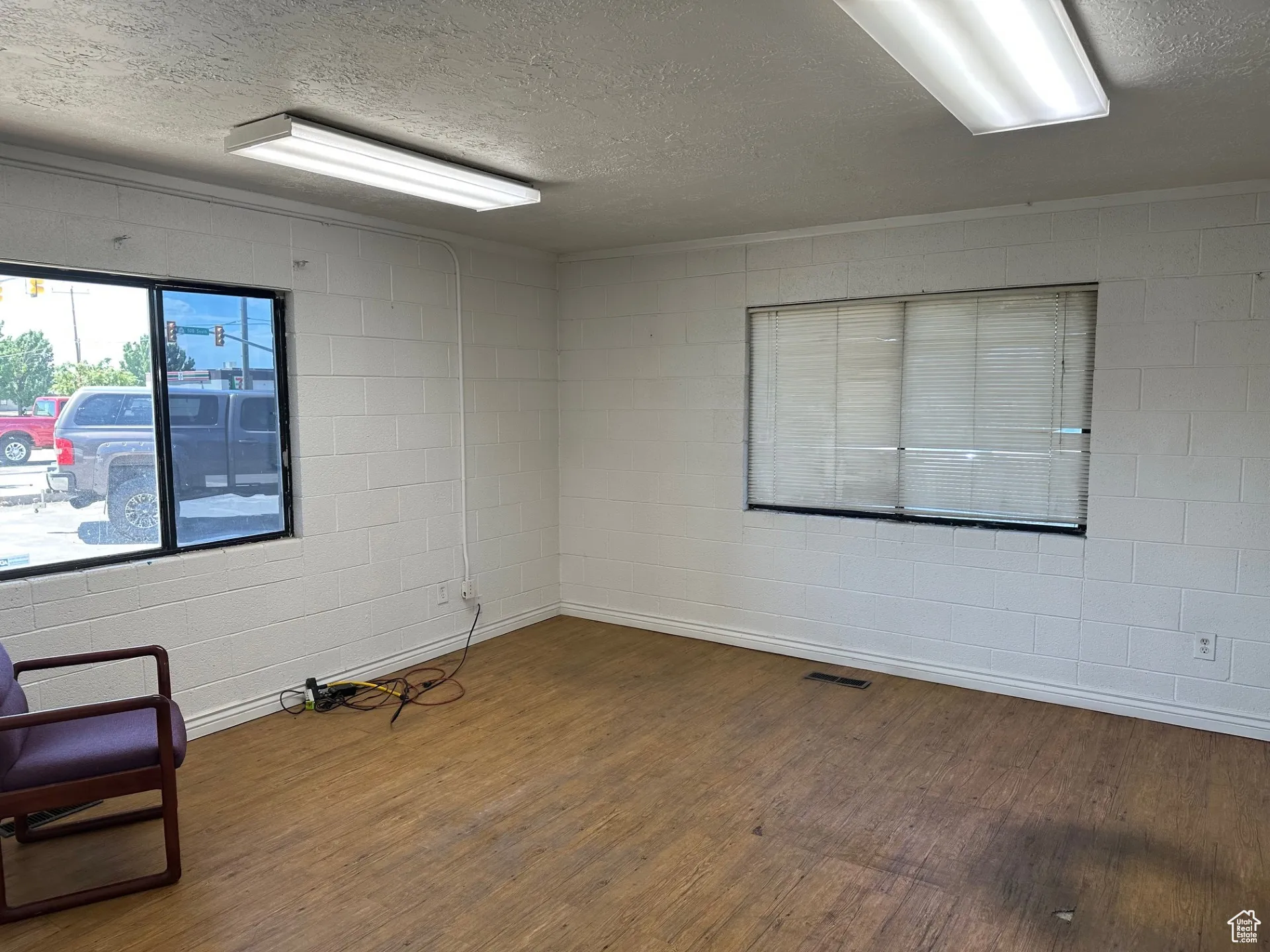 Empty room featuring a textured ceiling, wood finished floors, and concrete block wall