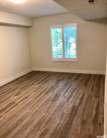 Unfurnished room with baseboards and dark wood-type flooring