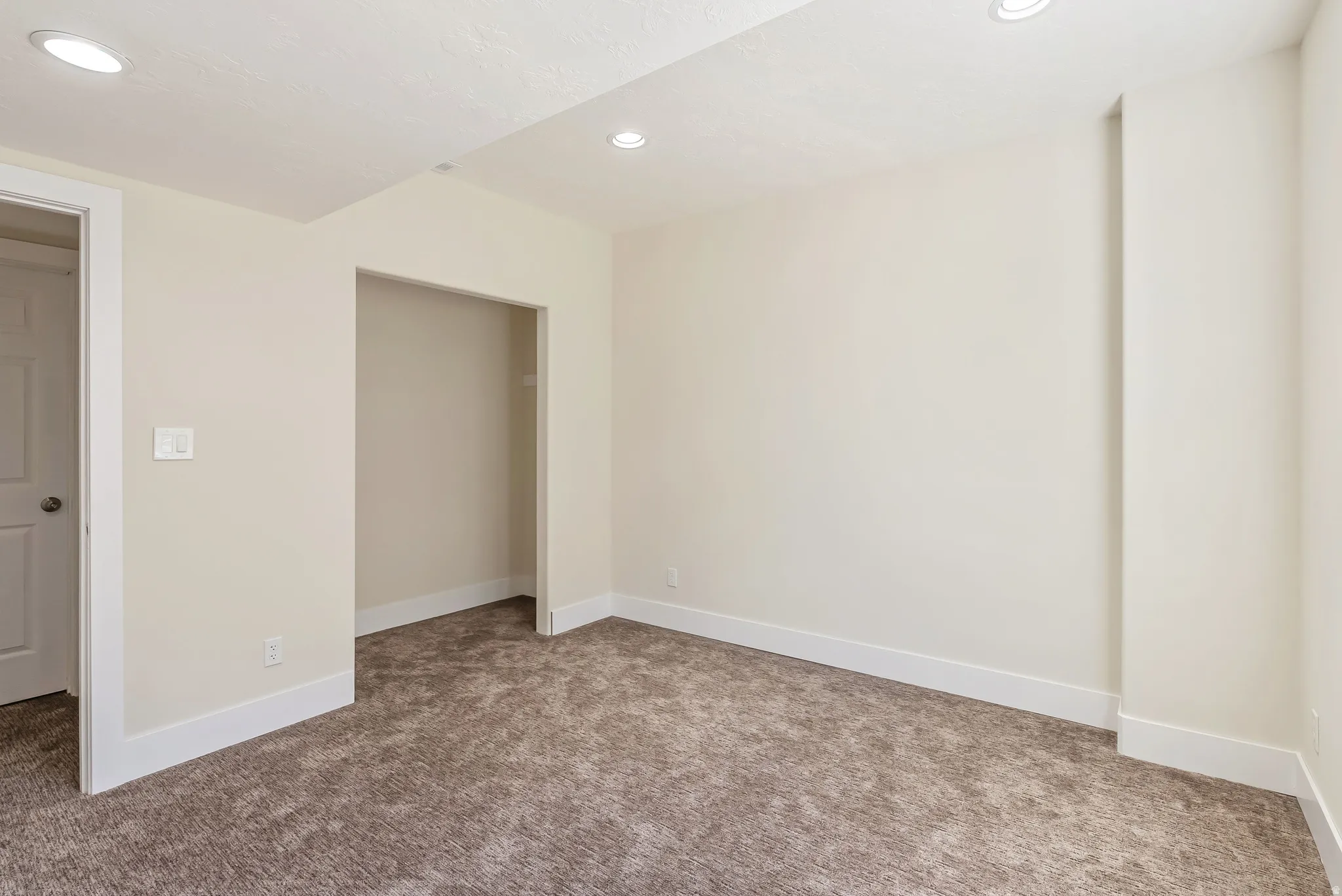 Neutral-toned room featuring recessed lighting, a neutral carpet, white baseboards, and a framed doorway