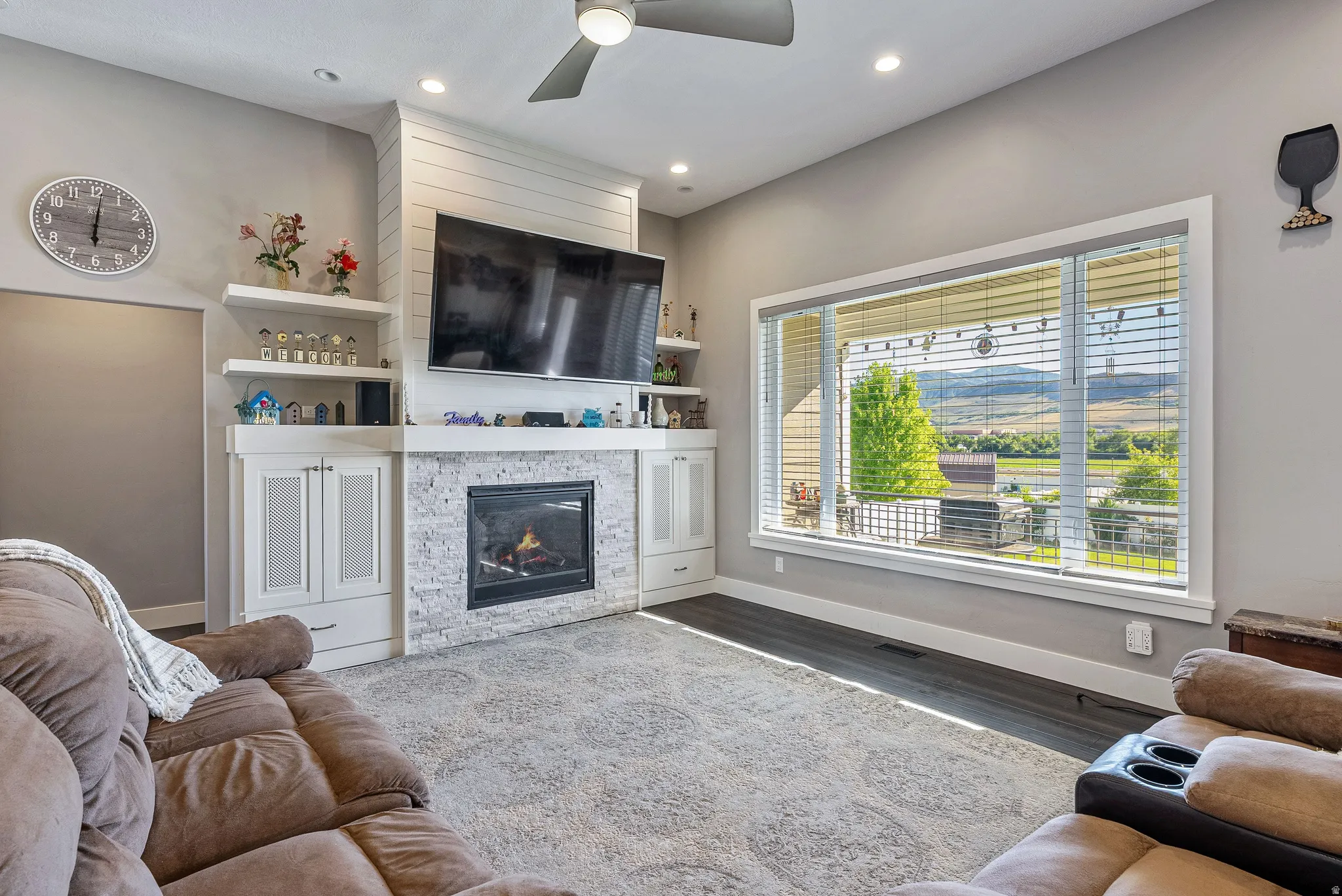 Living space featuring a stone-faced fireplace with hearth, built-in cabinetry, and white floating shelves