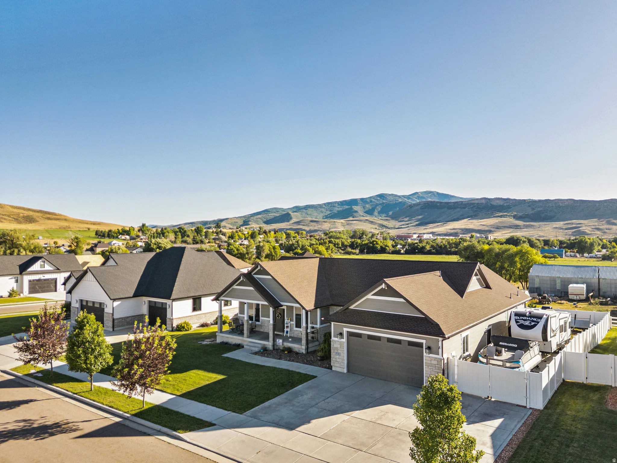 Contemporary residence featuring a covered front porch, an attached garage, and a fenced side yard