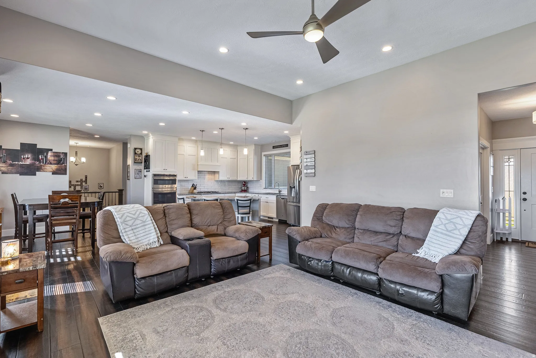 Spacious living area featuring dark wood-finish flooring, recessed lighting, and a ceiling fan