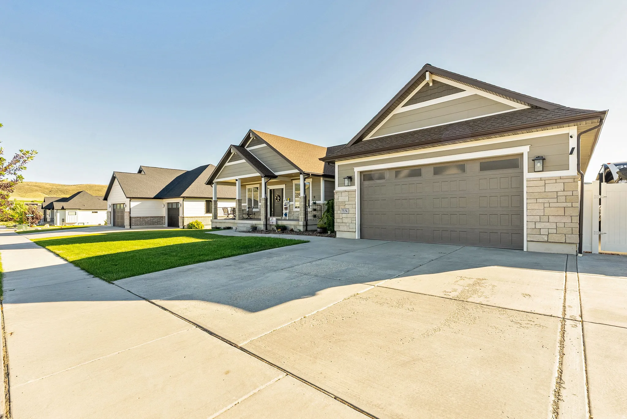 Modern Craftsman-style exterior featuring a prominent two-car garage with a panel door, stone veneer accents, and siding