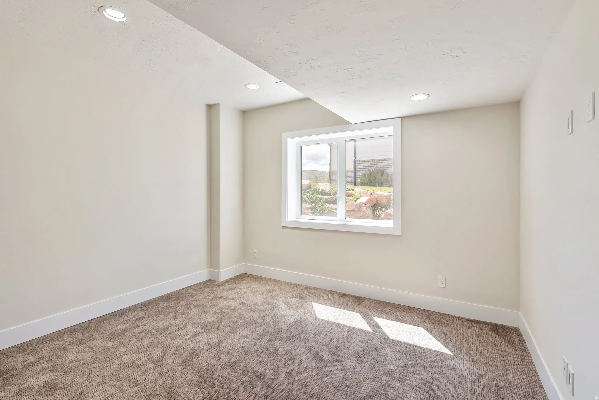 Carpeted room with recessed lighting, a white-framed window, and neutral wall paint