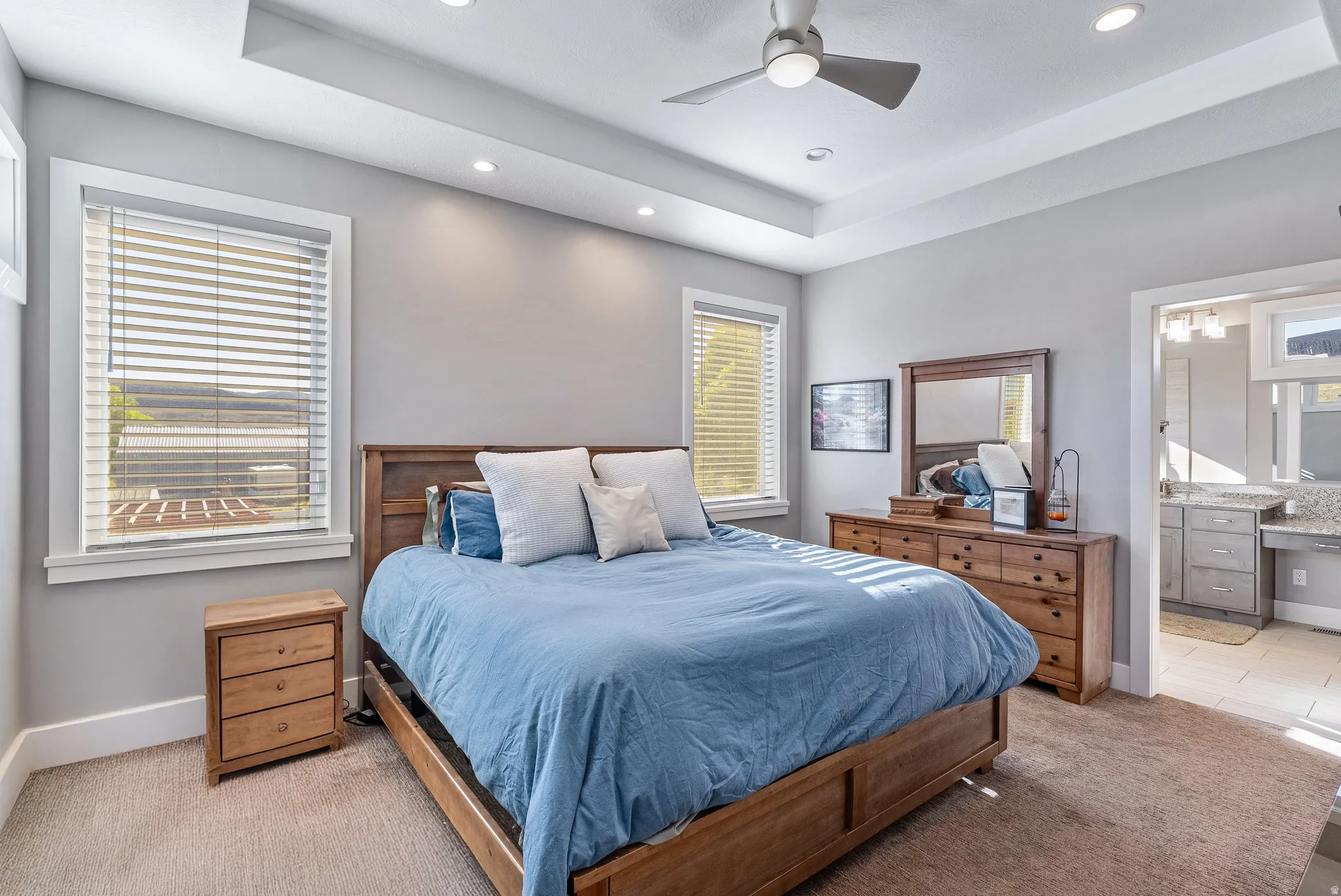 Carpeted bedroom with a tray ceiling and recessed lighting