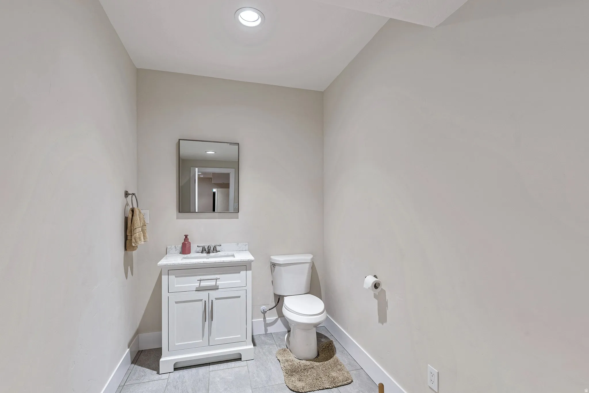 Powder room featuring a white single vanity with a stone countertop, an undermount sink, and a rectangular mirror