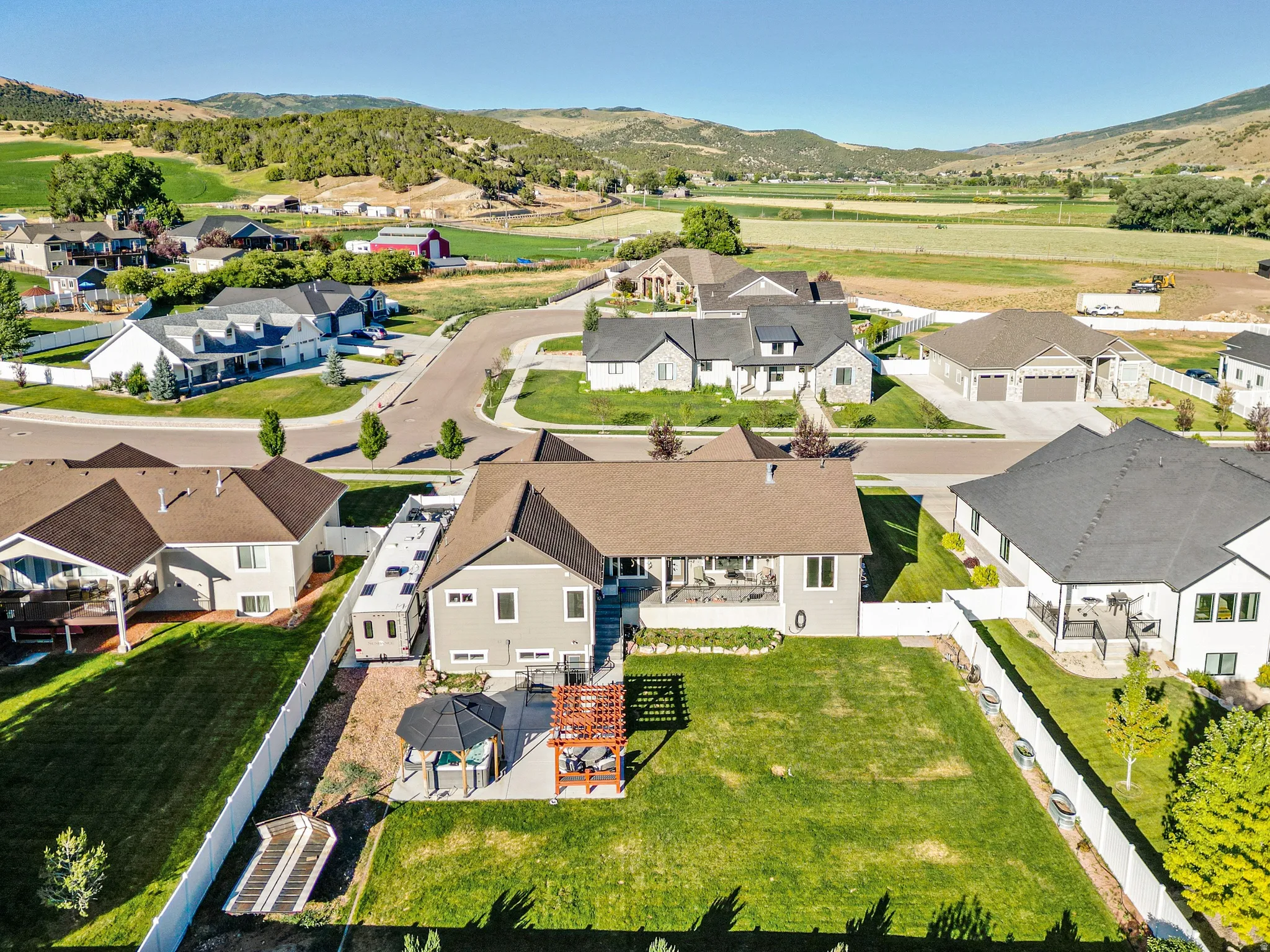Expansive backyard featuring a large green lawn, a covered patio, and a separate paved patio area with a gazebo and pergola