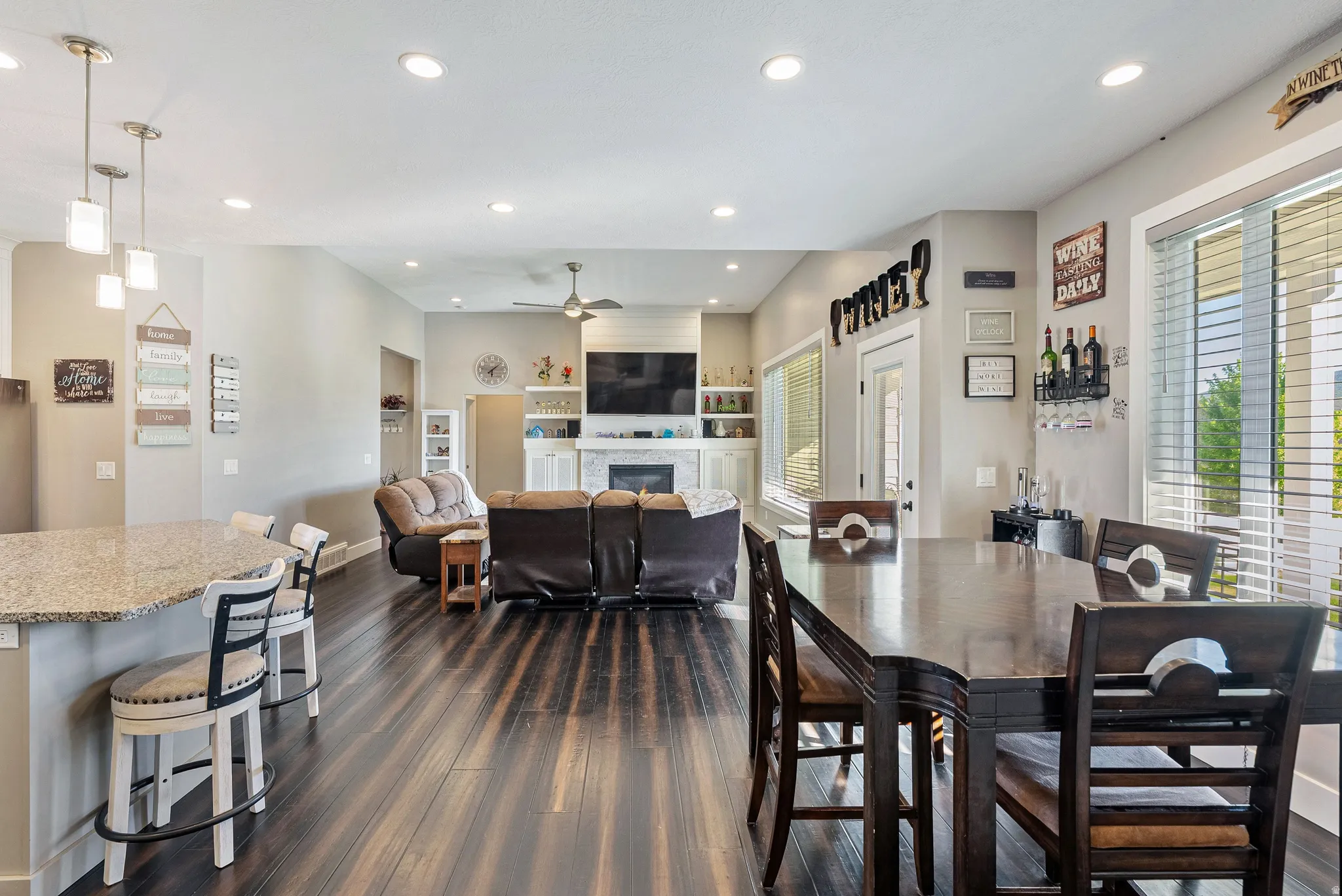 Open-concept living space featuring wood-finish flooring, recessed lighting, and a white stone fireplace with built-in shelving