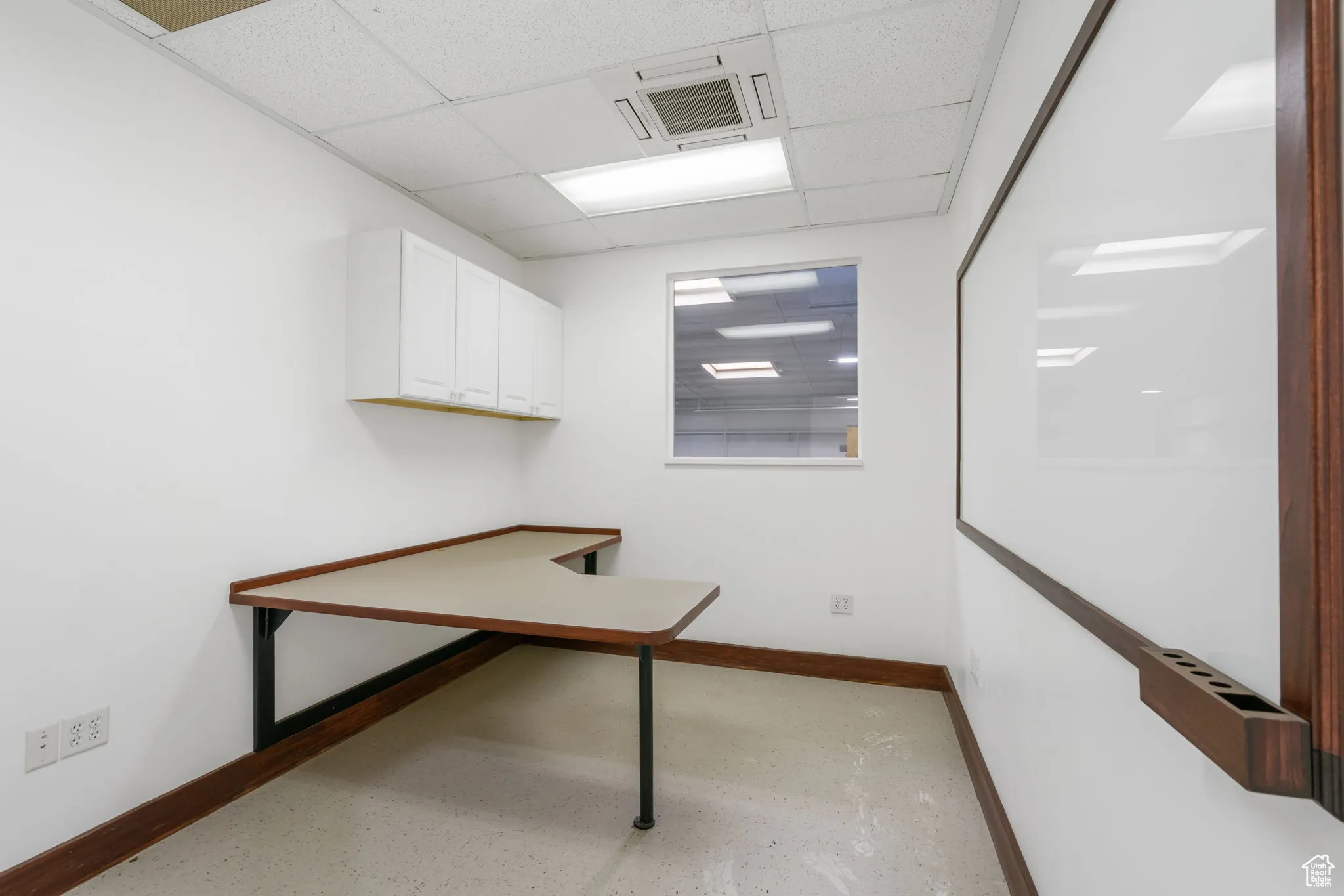 Unfurnished office featuring baseboards and a paneled ceiling