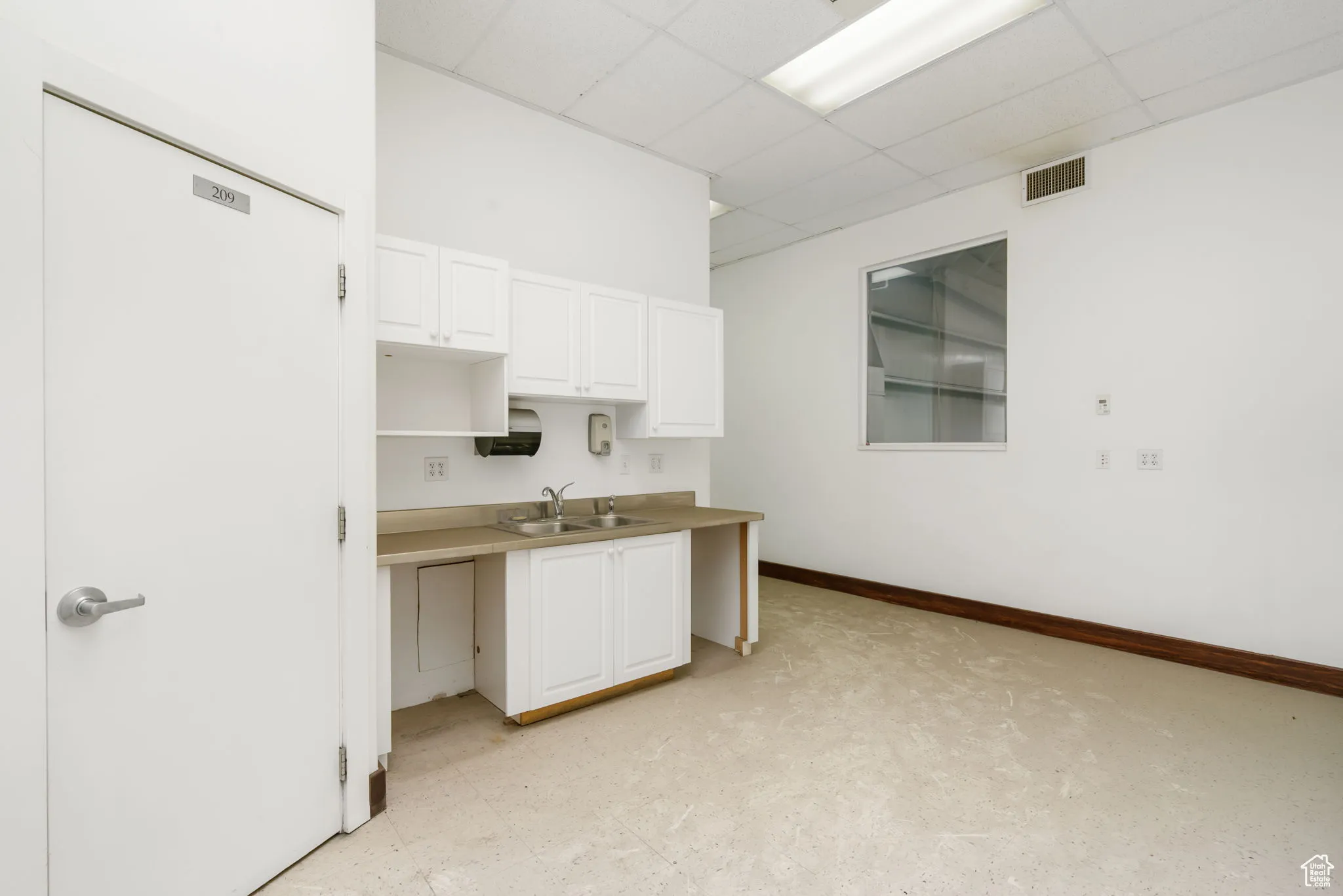 Kitchen featuring a paneled ceiling and white cabinets