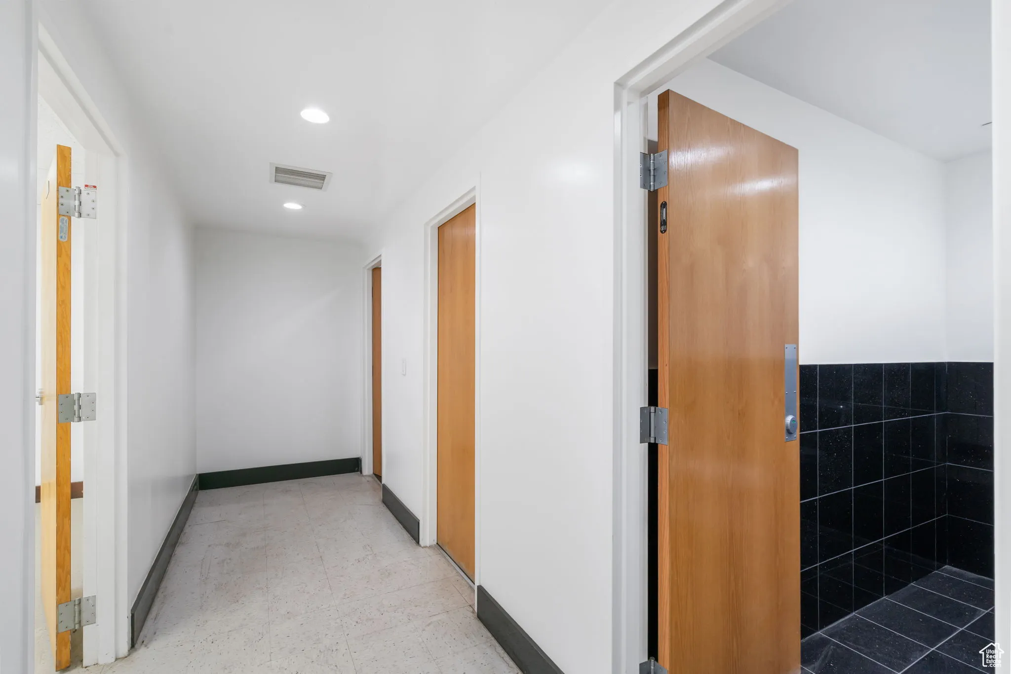 Hallway with light flooring and recessed lighting