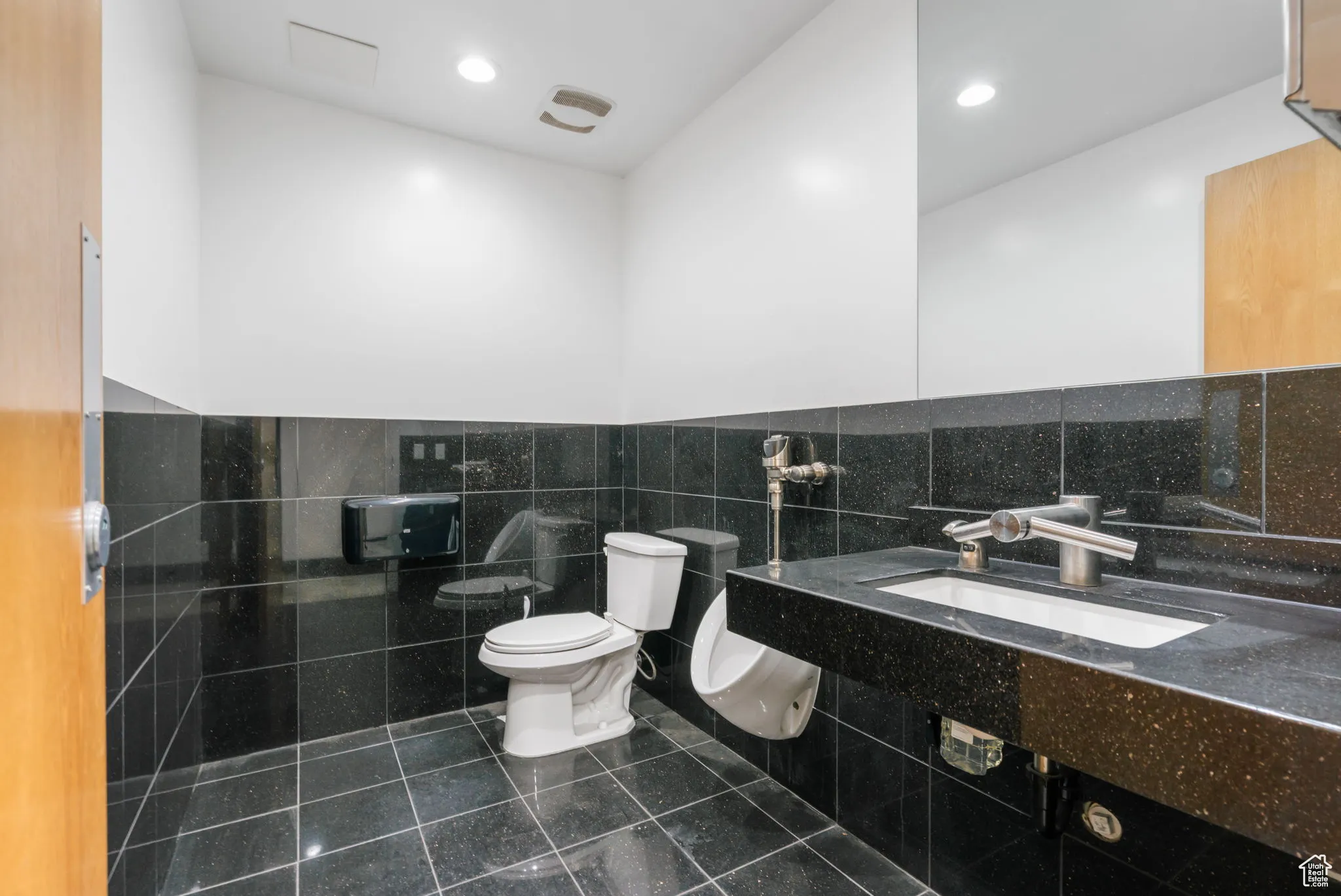 Half bath with tile walls, tile patterned flooring, and wainscoting