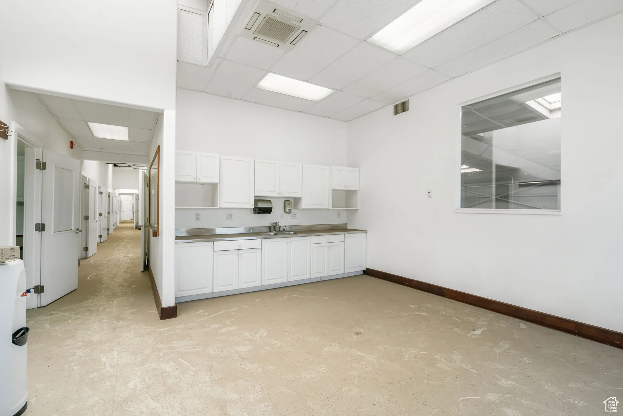 Kitchen with a drop ceiling, white cabinets, and open shelves