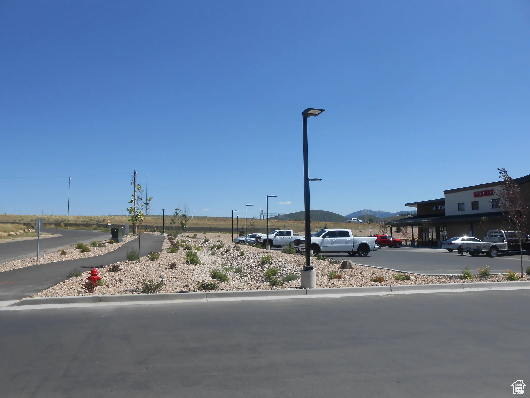 View of asphalt road with a mountain view, street lights, and curbs