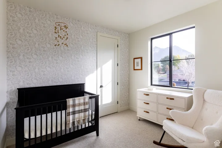 Bedroom with light carpet, a nursery area, a mountain view, and wallpapered walls