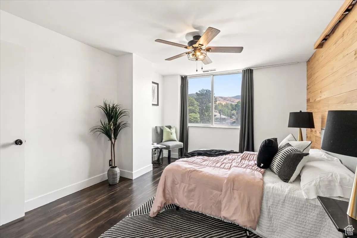 Bedroom featuring wood finished floors, wooden walls, and ceiling fan