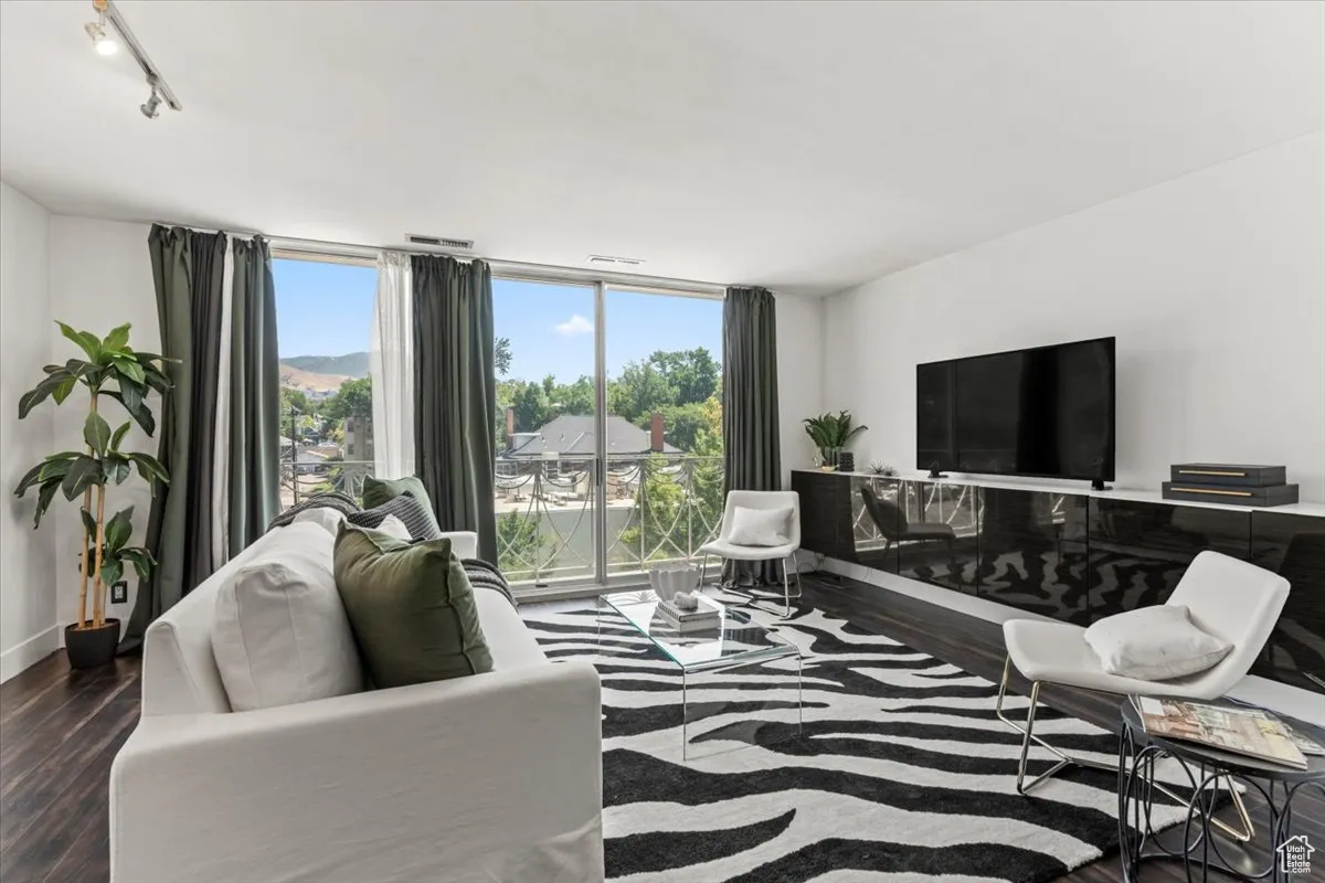 Living area featuring plenty of natural light, wood finished floors, rail lighting, and expansive windows