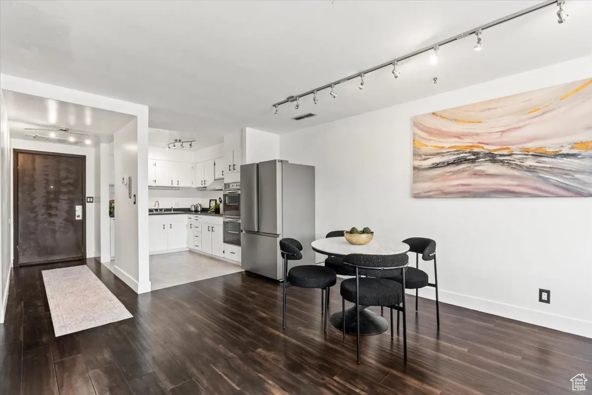 Dining area with dark wood-type flooring and track lighting