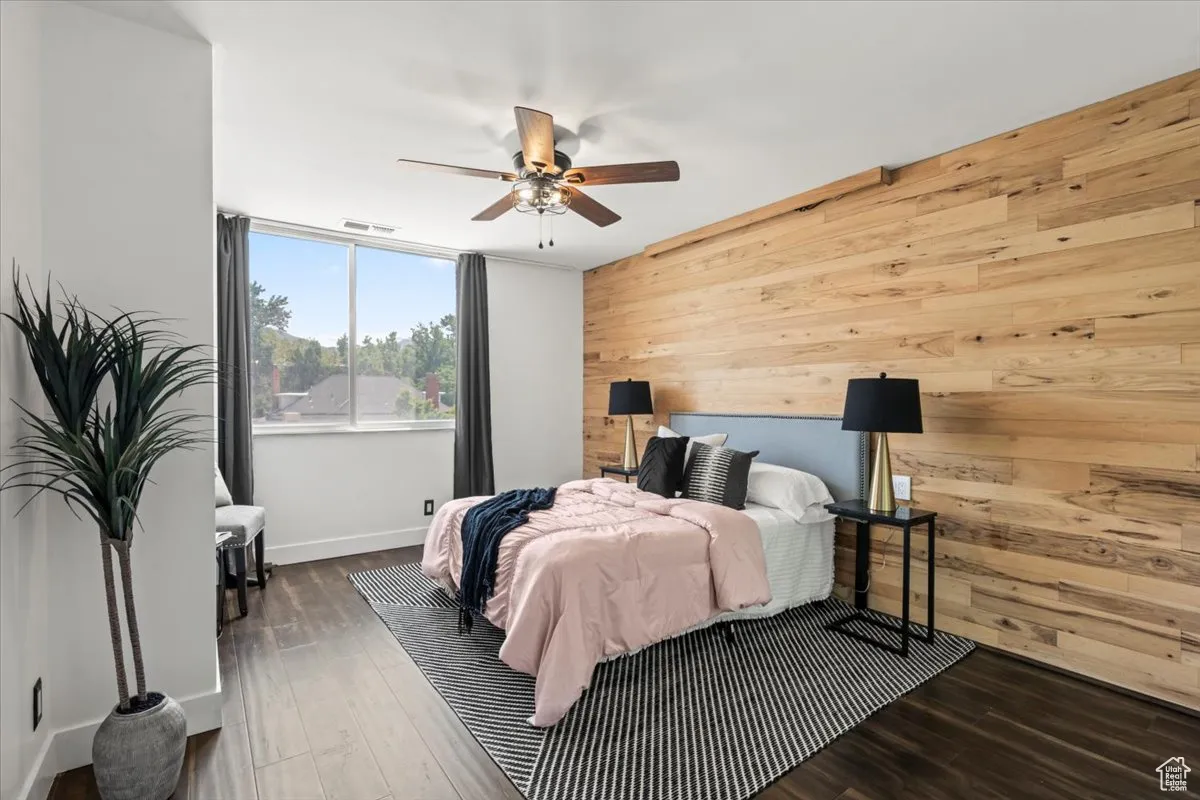 Bedroom featuring wood walls, wood finished floors, and ceiling fan