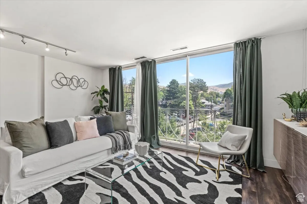 Living area with rail lighting, wood finished floors, and a wall of windows