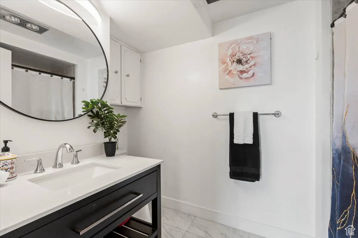 Full bath featuring vanity and marble finish floors
