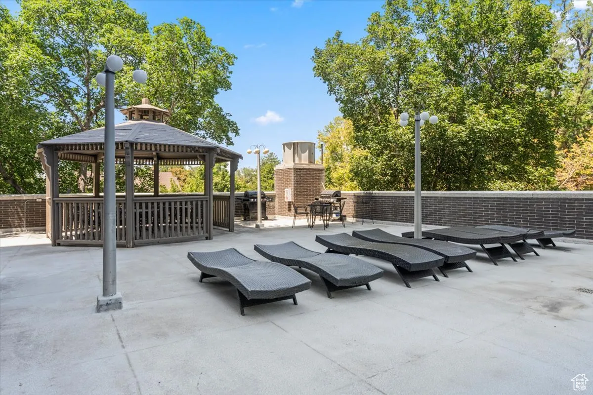 View of patio featuring a gazebo, an outdoor fireplace, and area for grilling