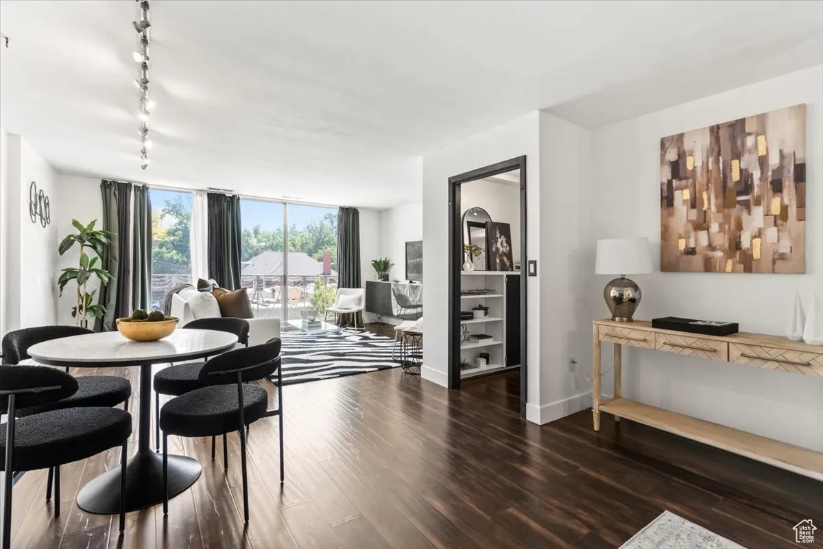 Dining room featuring rail lighting, wood finished floors, and a wall of windows