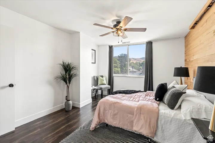 Bedroom featuring wood finished floors, wooden walls, and ceiling fan