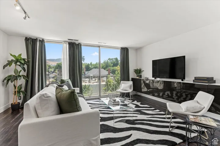 Living area featuring plenty of natural light, wood finished floors, rail lighting, and expansive windows