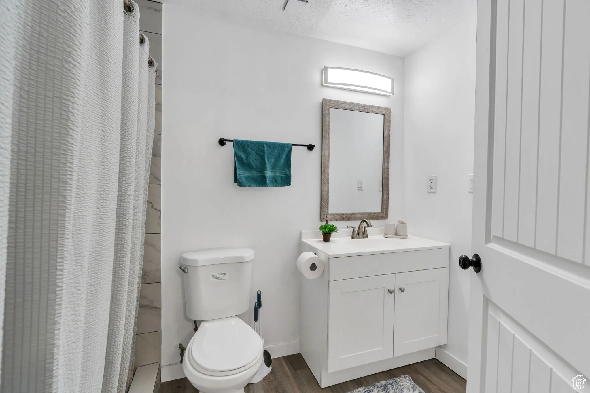 Bathroom featuring vanity, wood finished floors, a shower with curtain, and a textured ceiling