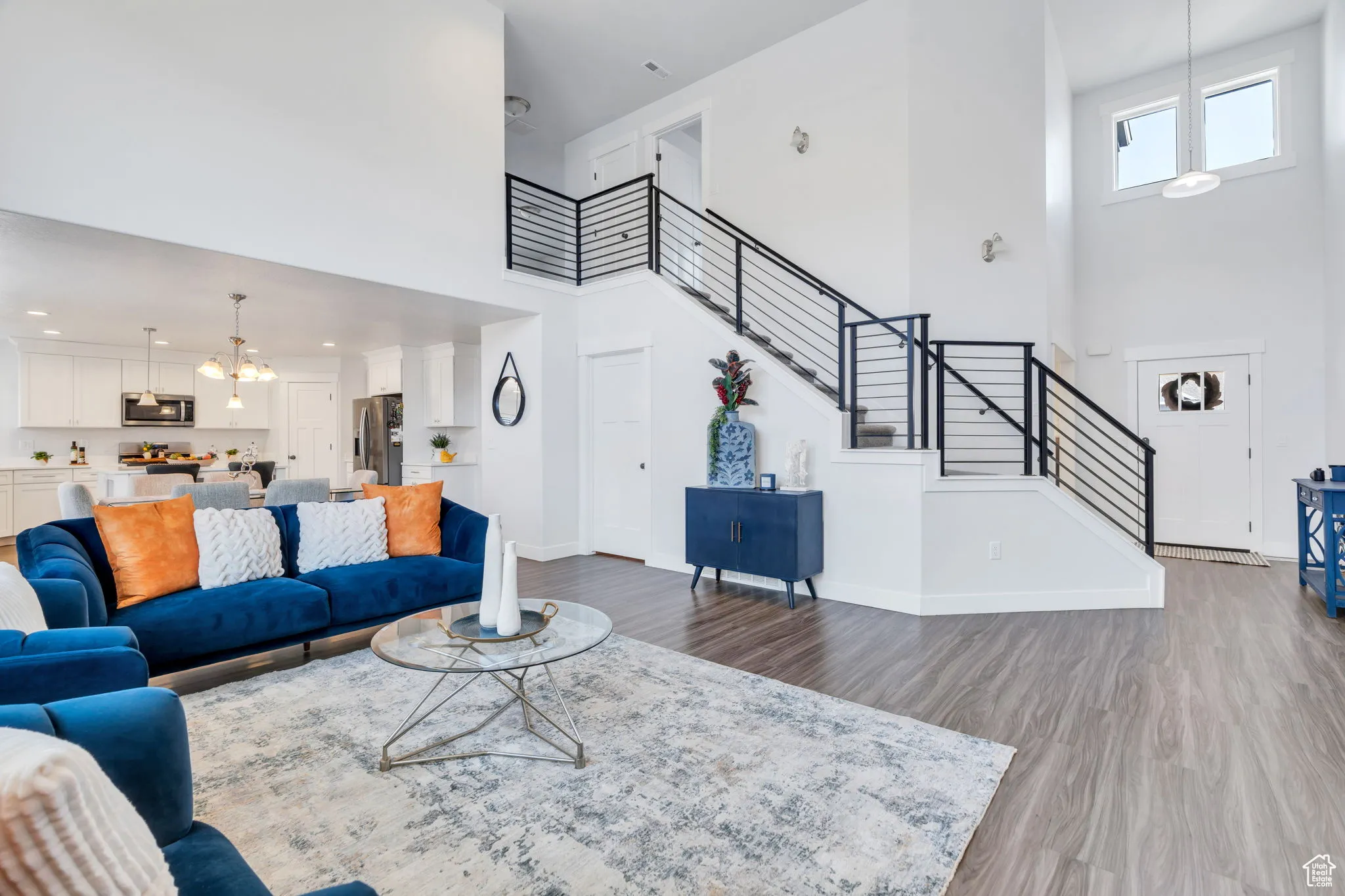 Living room featuring a towering ceiling, wood finished floors, stairs, and a chandelier