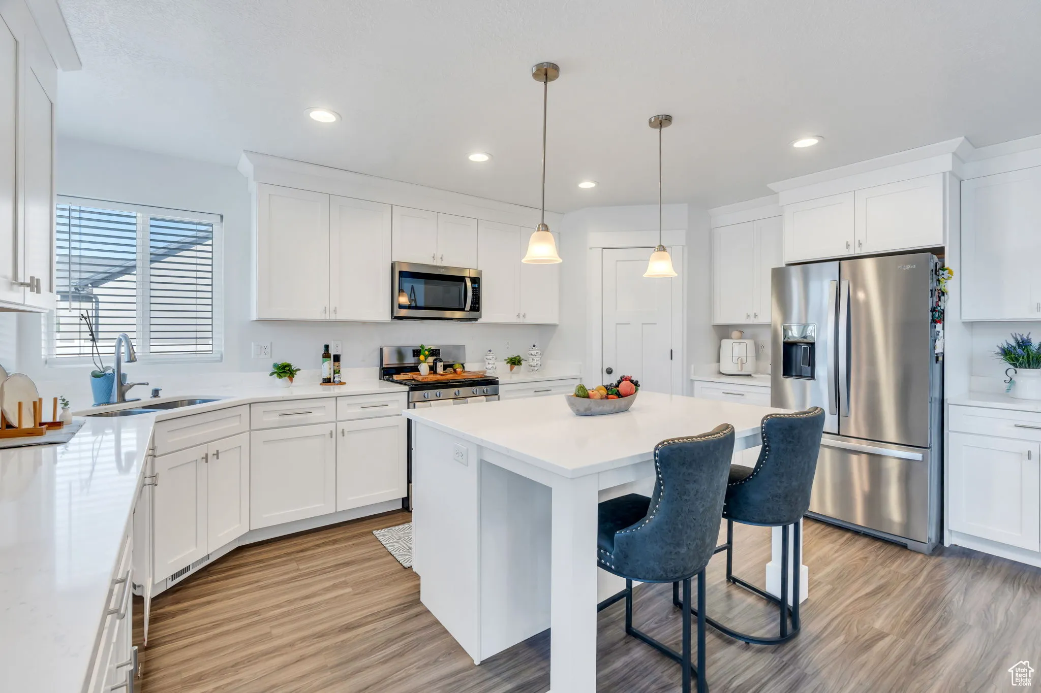 Kitchen featuring appliances with stainless steel finishes, white cabinetry, a breakfast bar area, a kitchen island, and light wood-type flooring