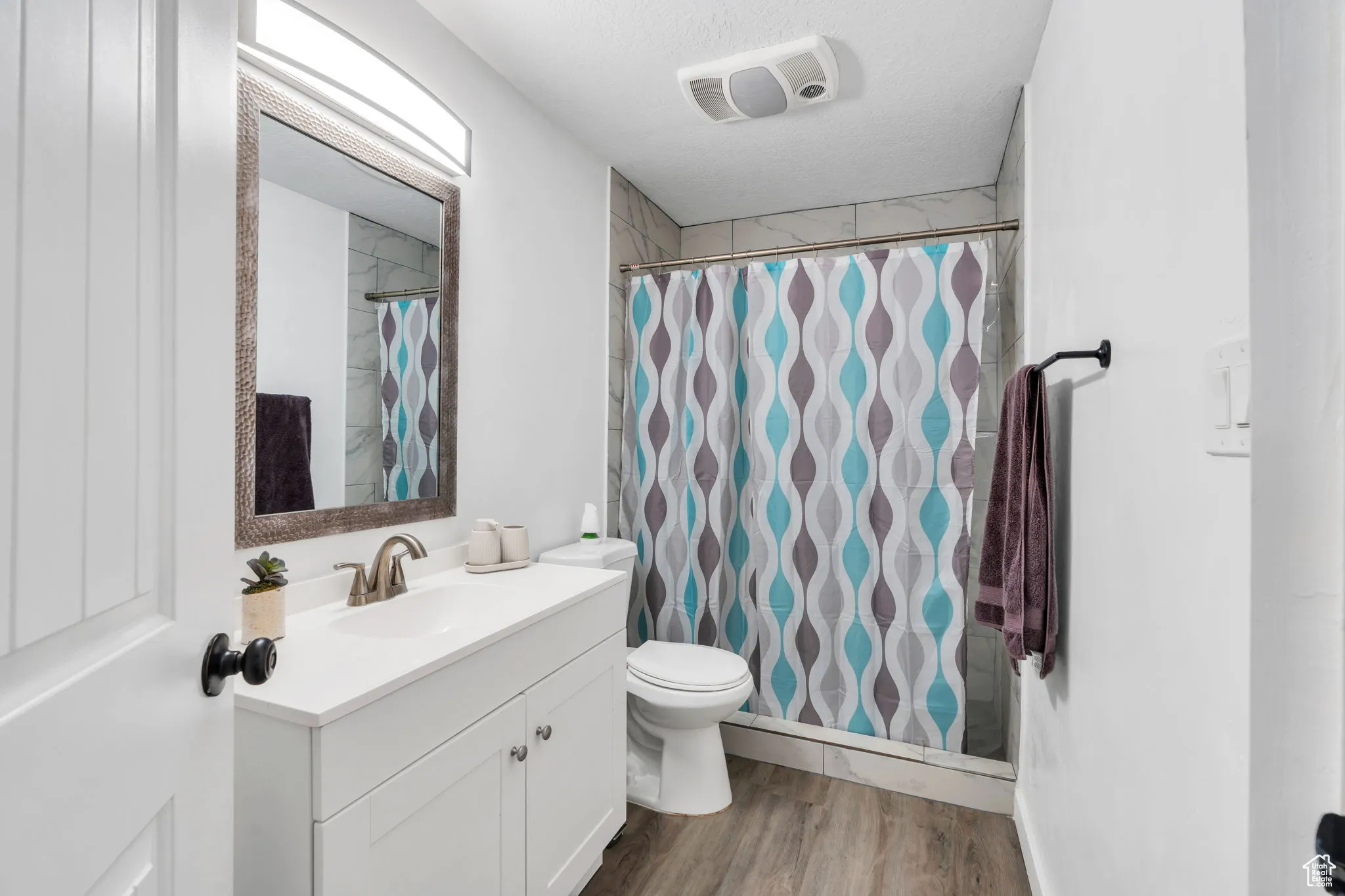 Full bath featuring vanity, wood finished floors, and curtained shower