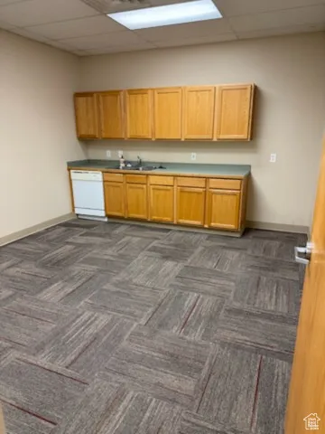 Kitchen featuring dark colored carpet, a drop ceiling, and white dishwasher