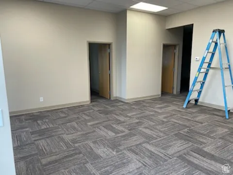 Empty room with a paneled ceiling and carpet floors