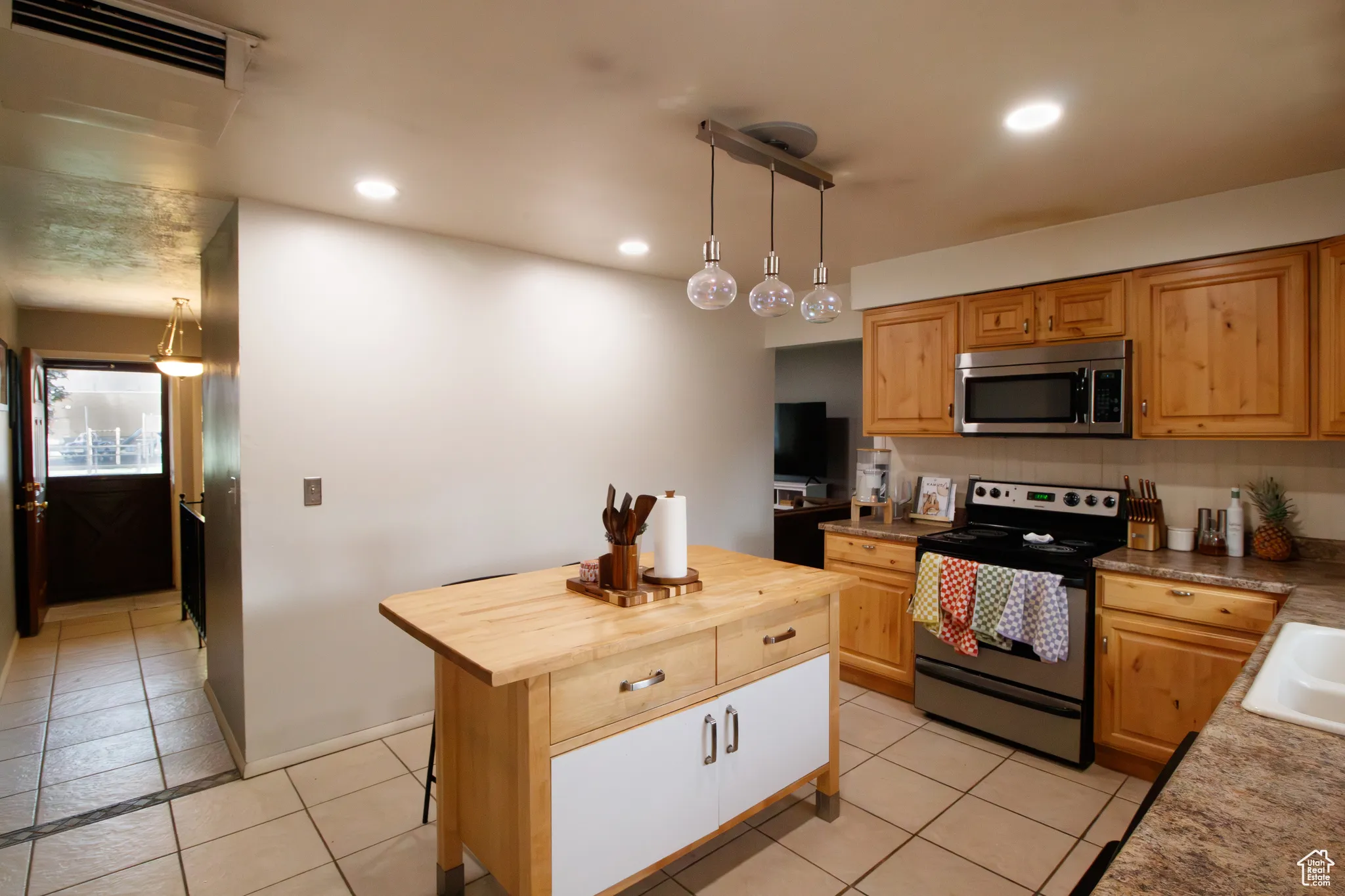 Kitchen with wood counters, stainless steel appliances, recessed lighting, pendant lighting, and a center island