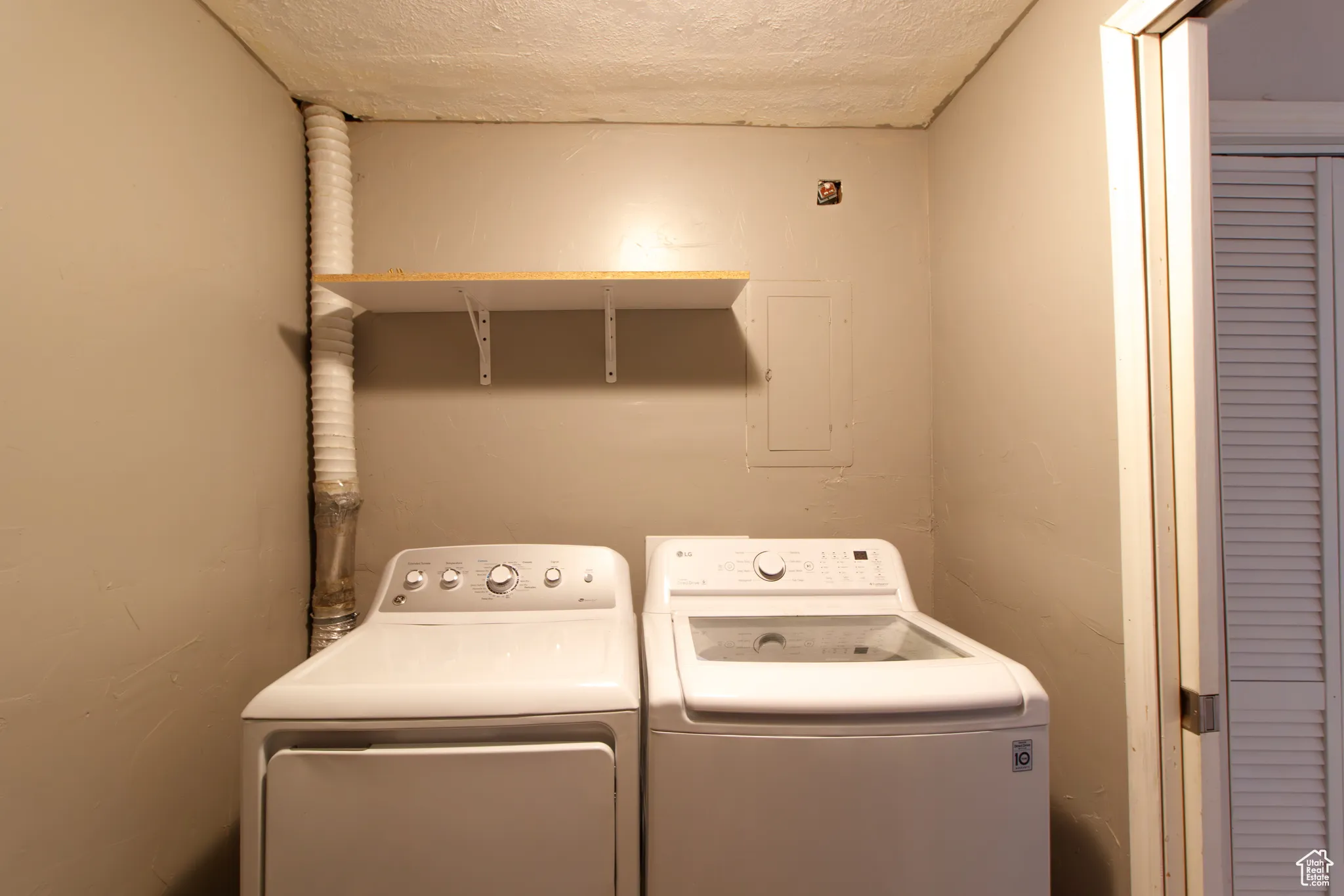 Laundry area with washing machine and clothes dryer, a textured ceiling, and electric panel