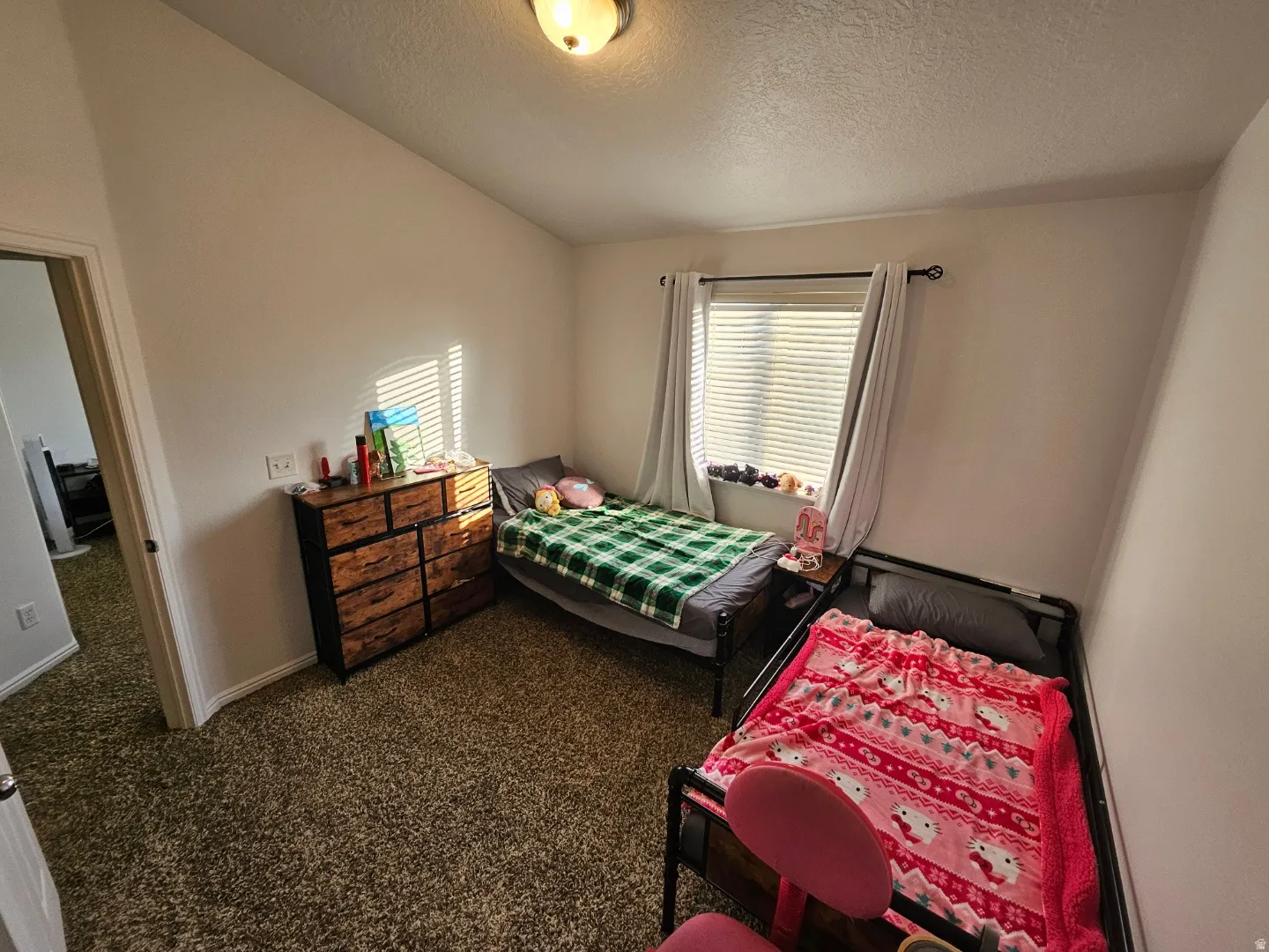 Bedroom with carpet flooring, a textured ceiling, and vaulted ceiling